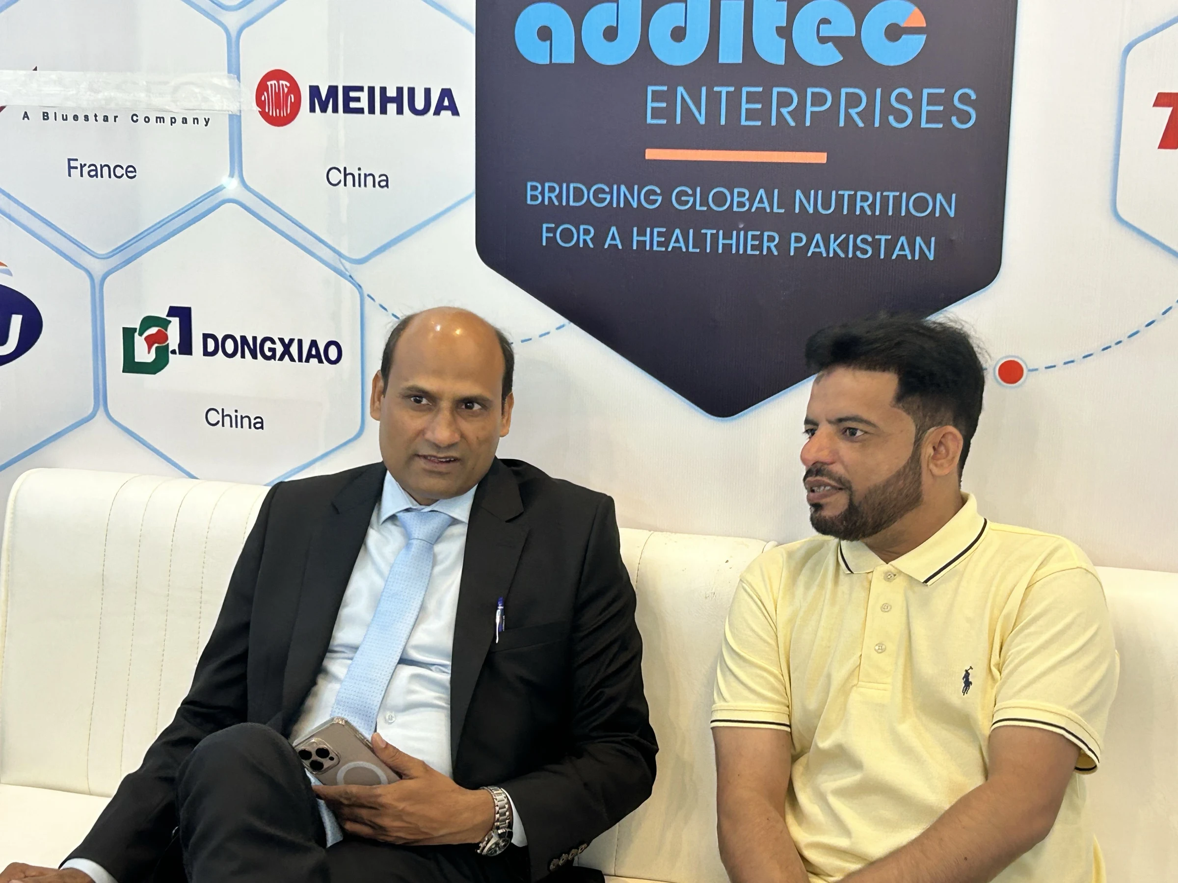 Two-person seated conversation at the Additec Enterprises booth on IPEX EXPO 2026 Day 02