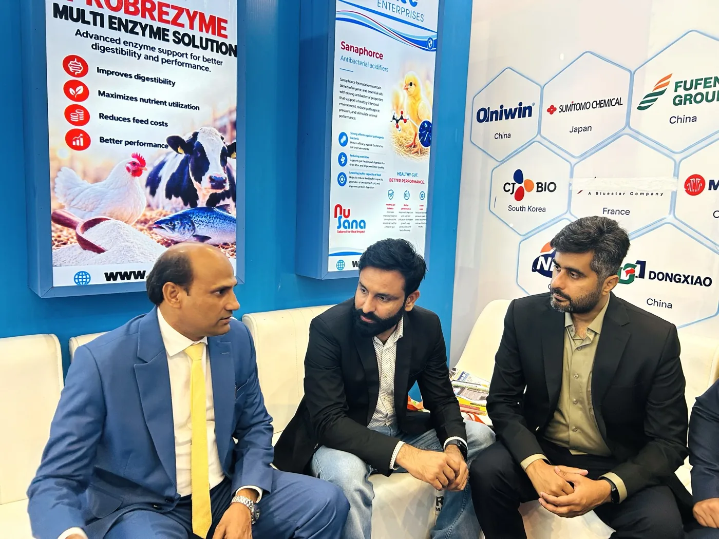 Business discussion at the Additec Enterprises booth with product panels visible